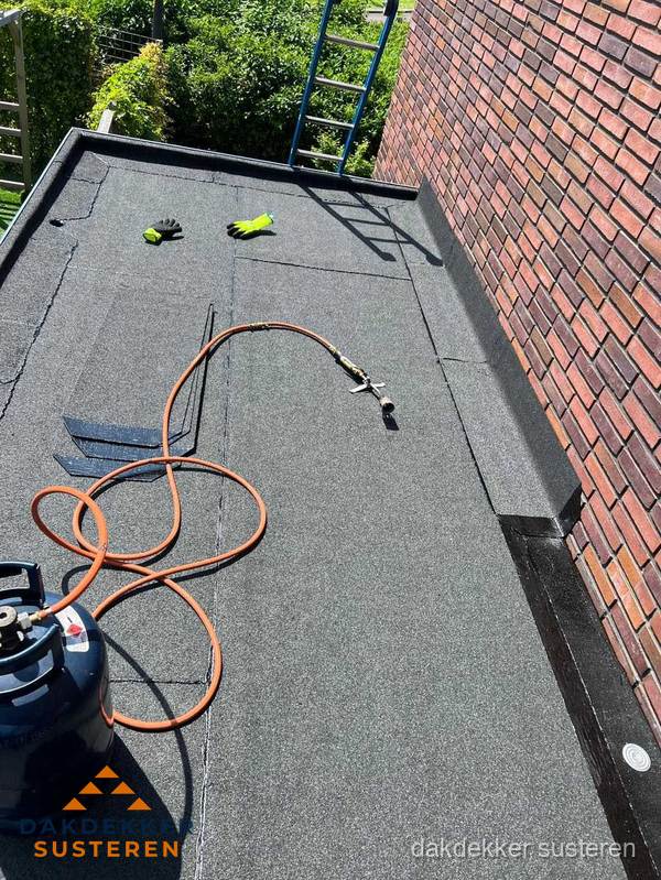 Plat dak met bitumen en brandgereedschap van dakdekkersbedrijf in Susteren