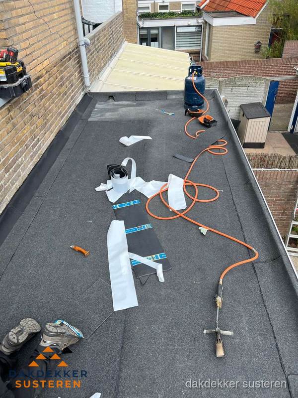 Dakdekkers bezig met bitumen dakbedekking in Susteren