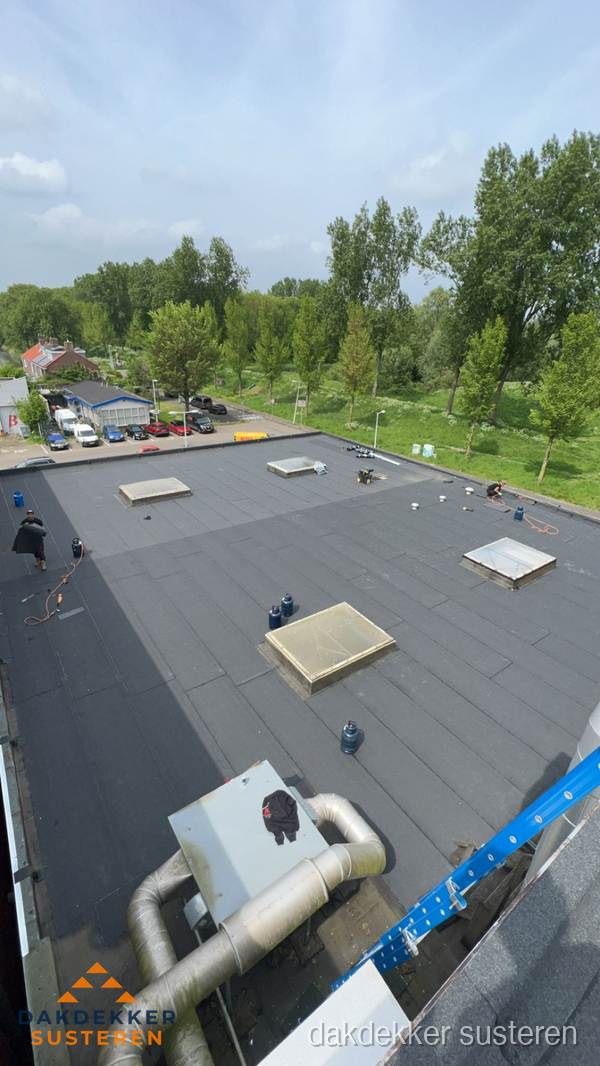 Dakdekker aan het werk op groot plat dak met bitumen in Susteren